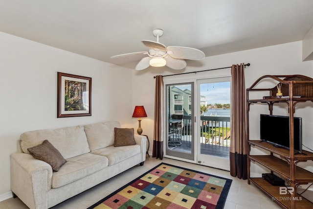 living area with ceiling fan, baseboards, and light tile patterned floors