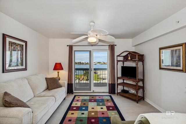 living area featuring light tile patterned floors, baseboards, and ceiling fan