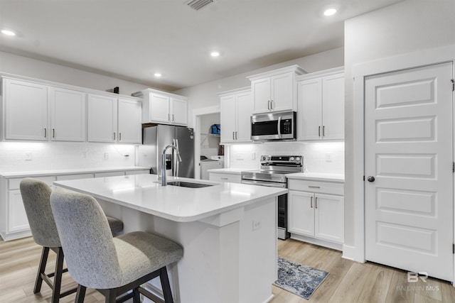9983 Willet Way, Foley, AL 36535 - kitchen featuring stainless steel appliances, washing machine and clothes dryer, an island with sink, decorative backsplash, and recessed lighting