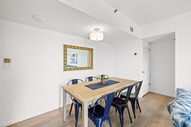 dining area with light hardwood / wood-style floors and a textured ceiling