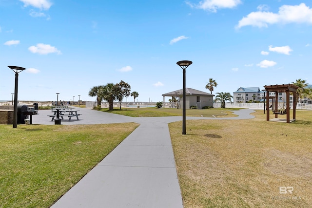 view of property's community featuring a pergola and a lawn