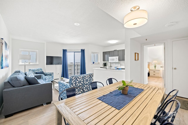 dining room with a textured ceiling and light wood-type flooring