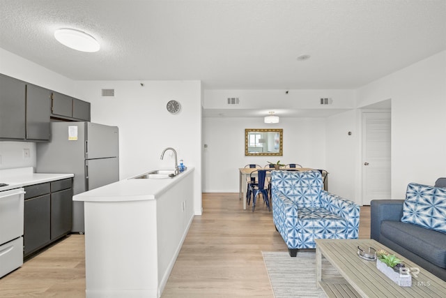 kitchen featuring a textured ceiling, sink, light hardwood / wood-style floors, and electric range