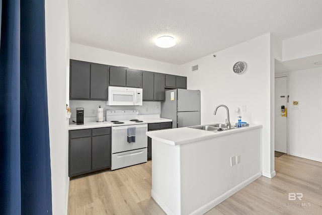 kitchen with white appliances, light wood-type flooring, and sink