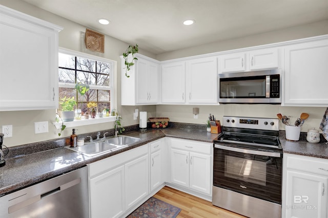 kitchen with stainless steel appliances, sink, light hardwood / wood-style flooring, and white cabinets