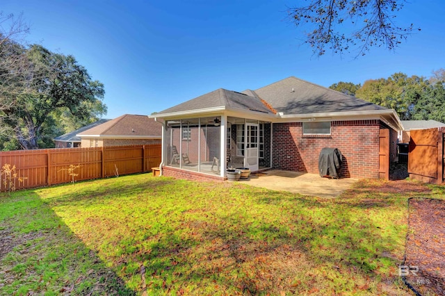 rear view of house with a sunroom, a patio area, and a lawn