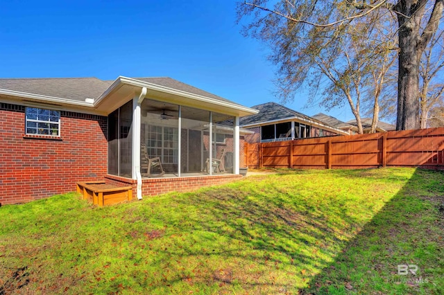 rear view of property with a sunroom, a yard, and ceiling fan