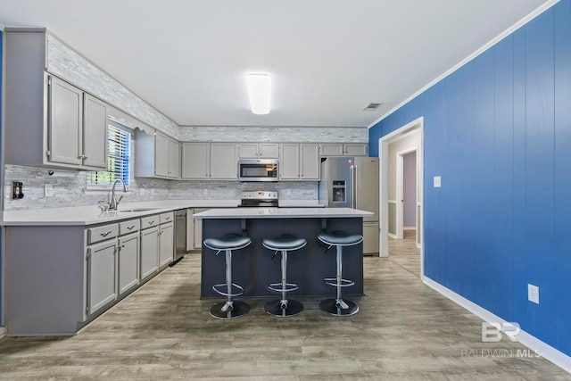 kitchen featuring sink, a center island, wood-type flooring, a breakfast bar area, and appliances with stainless steel finishes