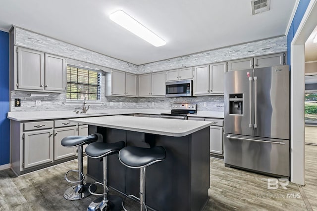 kitchen featuring a breakfast bar, stainless steel appliances, sink, hardwood / wood-style flooring, and a center island