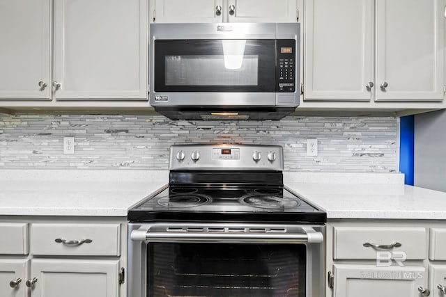 kitchen with light stone countertops, appliances with stainless steel finishes, and backsplash