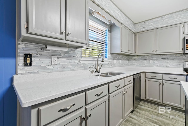 kitchen with gray cabinetry, light stone countertops, sink, light hardwood / wood-style flooring, and decorative backsplash