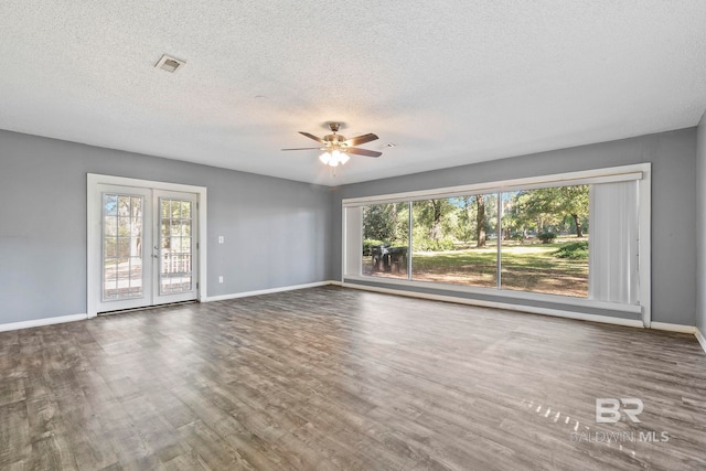 spare room featuring ceiling fan, dark hardwood / wood-style flooring, a textured ceiling, and french doors