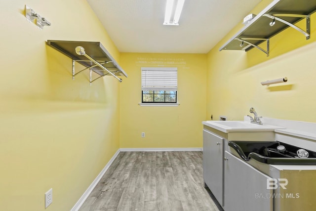 clothes washing area featuring light hardwood / wood-style floors and sink