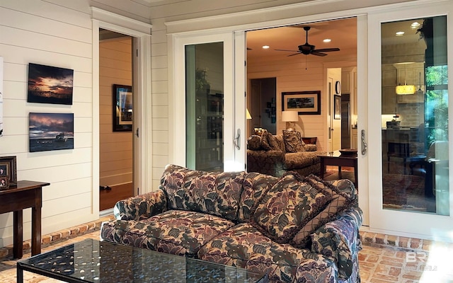 living room featuring ceiling fan and wooden walls