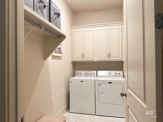 clothes washing area featuring cabinets and washer and clothes dryer