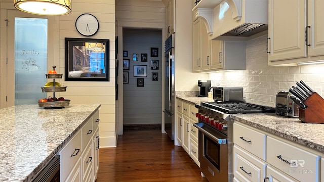 kitchen featuring backsplash, light stone counters, custom exhaust hood, premium appliances, and dark wood-type flooring