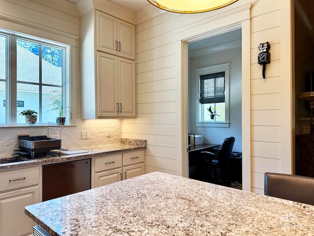 kitchen featuring a wealth of natural light, light stone counters, and wood walls