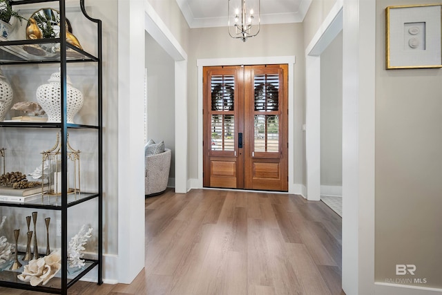 entryway featuring a chandelier, french doors, light hardwood / wood-style flooring, and crown molding