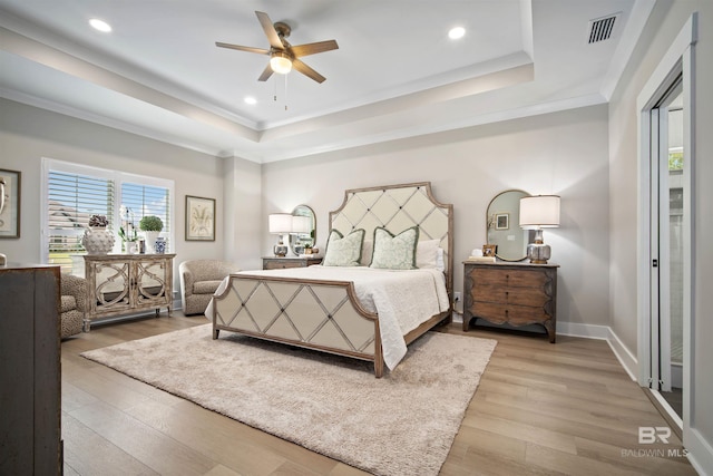 bedroom with wood-type flooring, a tray ceiling, and ceiling fan