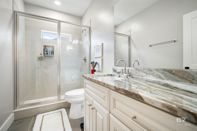 bathroom featuring tile patterned flooring, vanity, a shower with shower door, and toilet