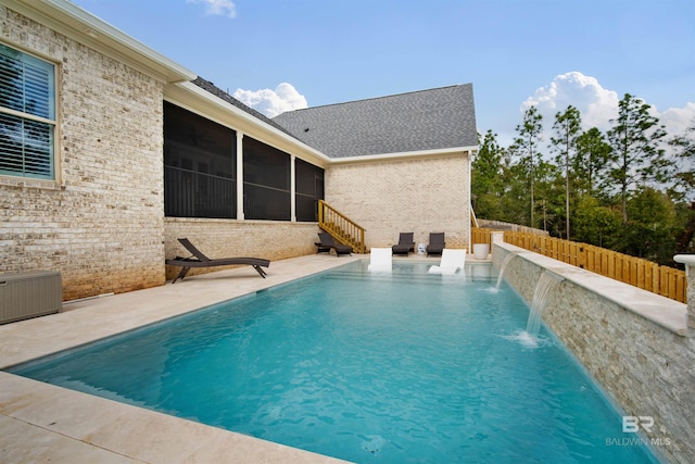 view of swimming pool featuring pool water feature, a sunroom, and a patio area