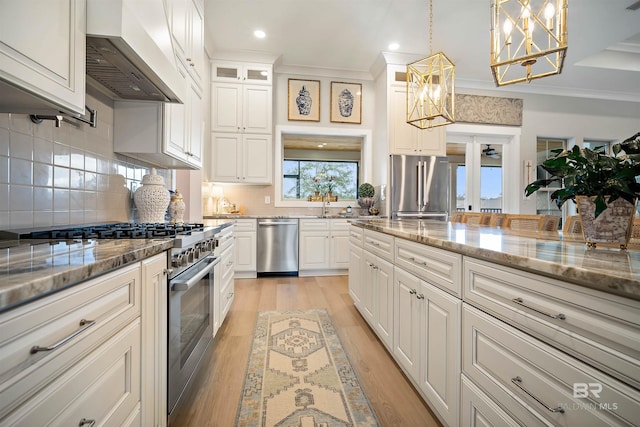 kitchen featuring custom exhaust hood, high end appliances, decorative backsplash, decorative light fixtures, and light stone counters