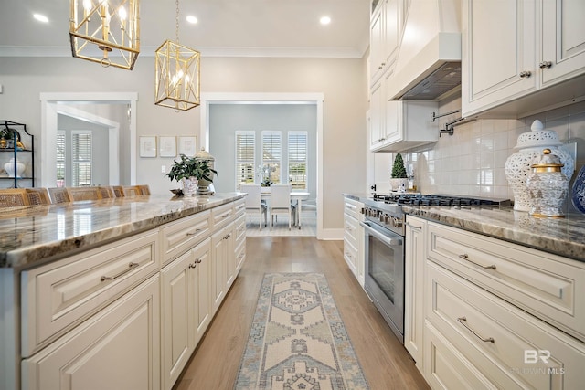 kitchen with pendant lighting, high end stainless steel range, decorative backsplash, dark stone countertops, and custom range hood