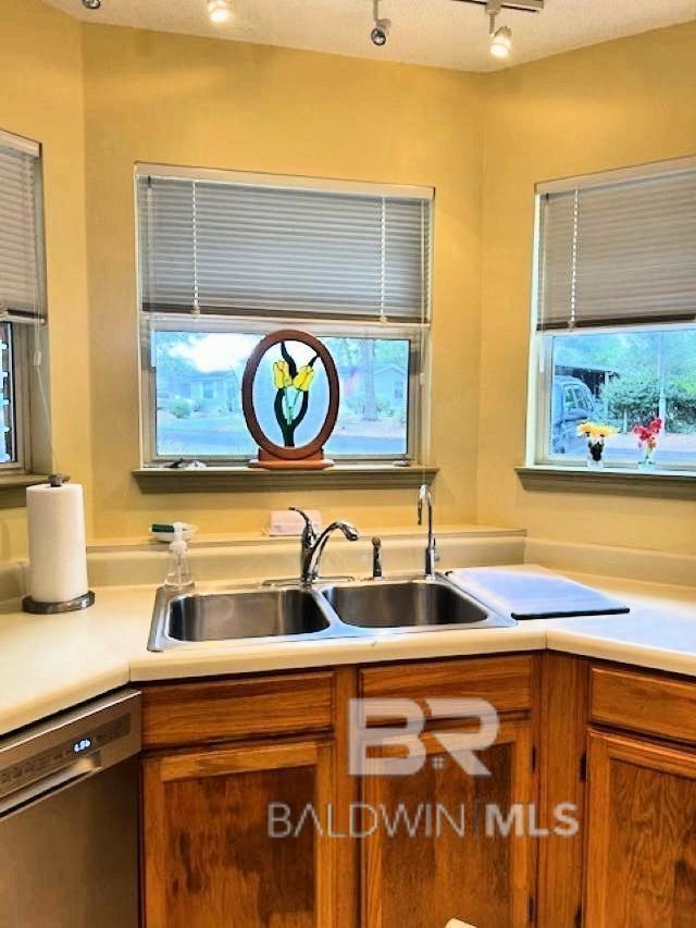 kitchen with sink, dishwasher, plenty of natural light, and rail lighting