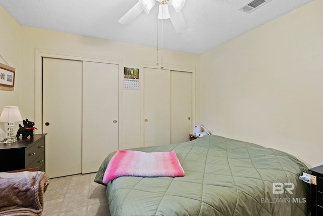 bedroom with ceiling fan and multiple closets