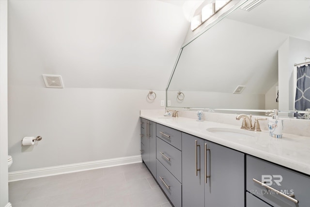 bathroom featuring tile patterned flooring, vaulted ceiling, double sink vanity, and toilet