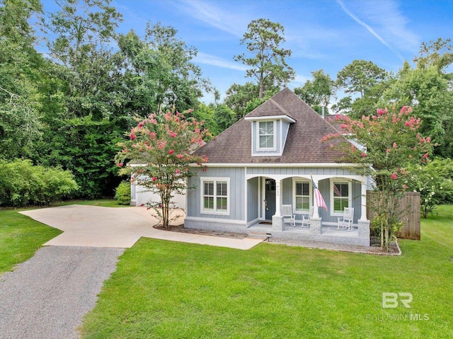 view of front of property with a porch, a garage, and a front lawn