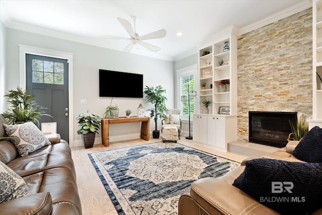 living room with a tile fireplace, crown molding, ceiling fan, and a wealth of natural light