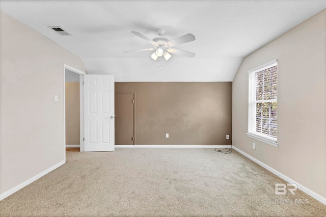 empty room with ceiling fan, lofted ceiling, carpet flooring, and a textured ceiling