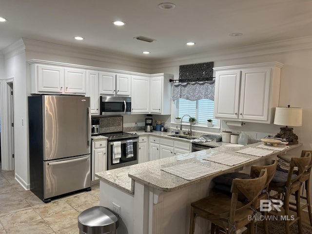 kitchen featuring a peninsula, a sink, white cabinetry, appliances with stainless steel finishes, and crown molding