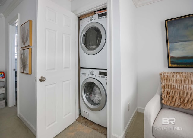 laundry area with stacked washer / drying machine, laundry area, and baseboards