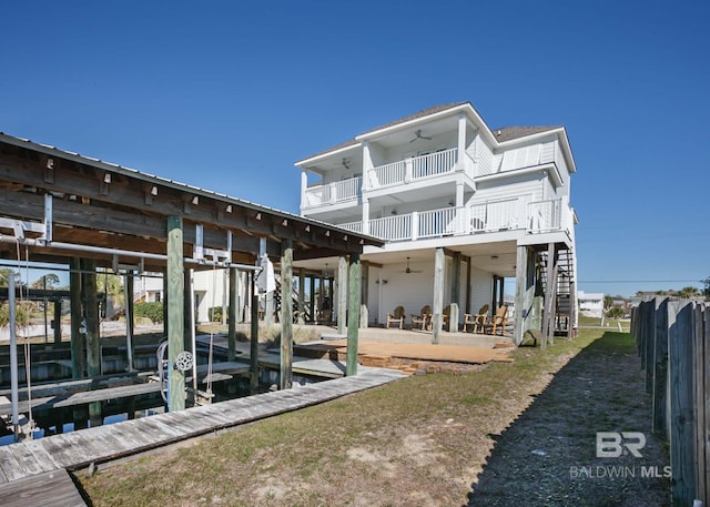 back of house with ceiling fan, boat lift, a patio area, and stairs