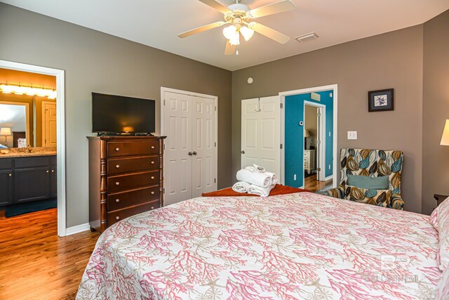 bedroom with a closet, ensuite bath, ceiling fan, and wood-type flooring