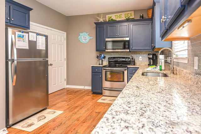 kitchen featuring sink, light hardwood / wood-style flooring, stainless steel appliances, backsplash, and blue cabinetry