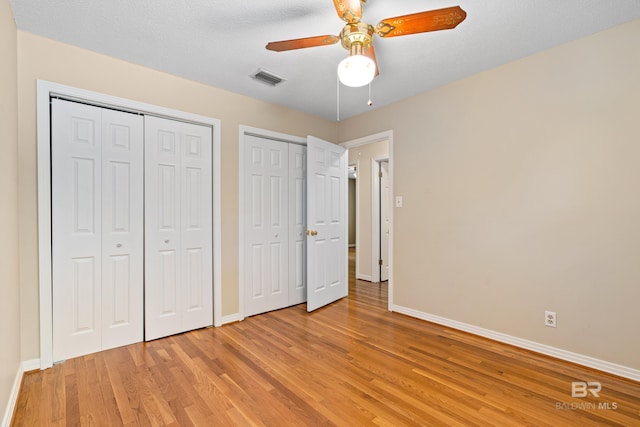 606 Fairhope Ave, Fairhope, AL 36532 - unfurnished bedroom with multiple closets, baseboards, light wood-style floors, and a ceiling fan