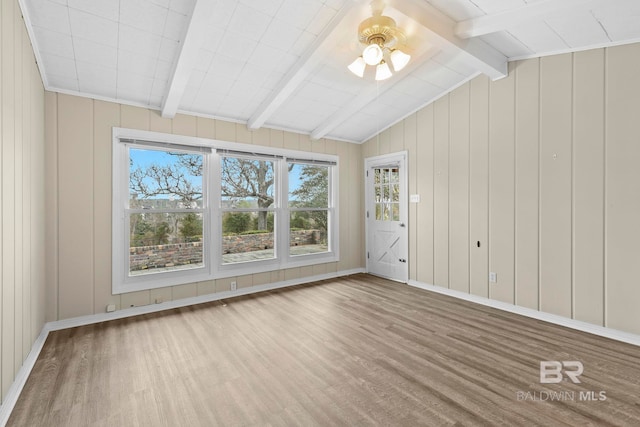 empty room featuring ceiling fan, wood-type flooring, and vaulted ceiling with beams