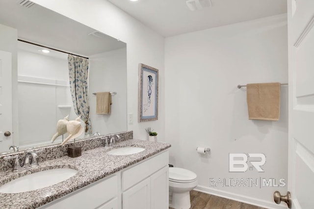 bathroom with hardwood / wood-style flooring, vanity, walk in shower, and toilet