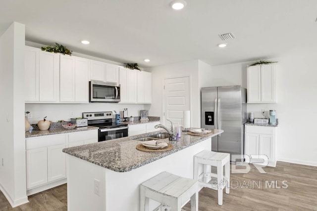 kitchen with sink, a center island with sink, white cabinets, and appliances with stainless steel finishes