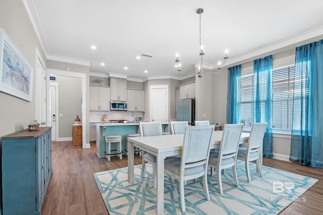 dining room featuring crown molding, a notable chandelier, and light wood-type flooring