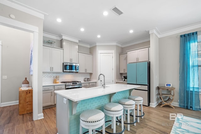 kitchen featuring sink, light hardwood / wood-style floors, a breakfast bar area, a center island with sink, and appliances with stainless steel finishes