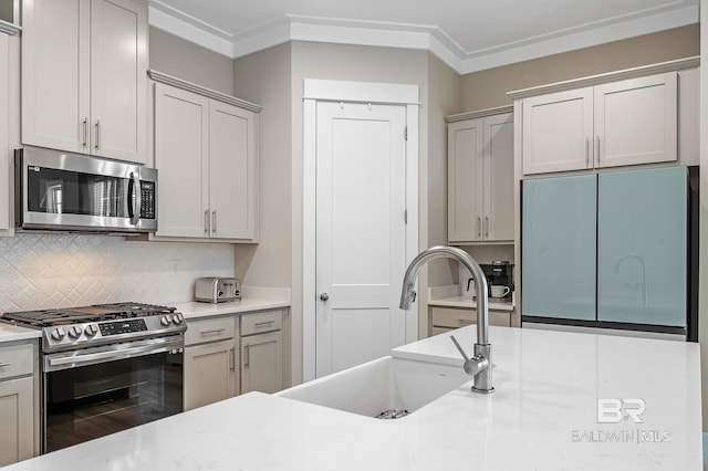 kitchen with tasteful backsplash, sink, ornamental molding, and appliances with stainless steel finishes