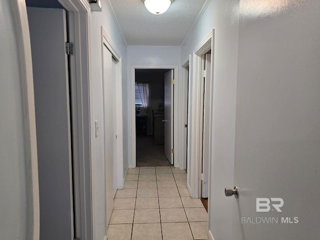 hallway featuring crown molding, light tile patterned floors, and a textured ceiling