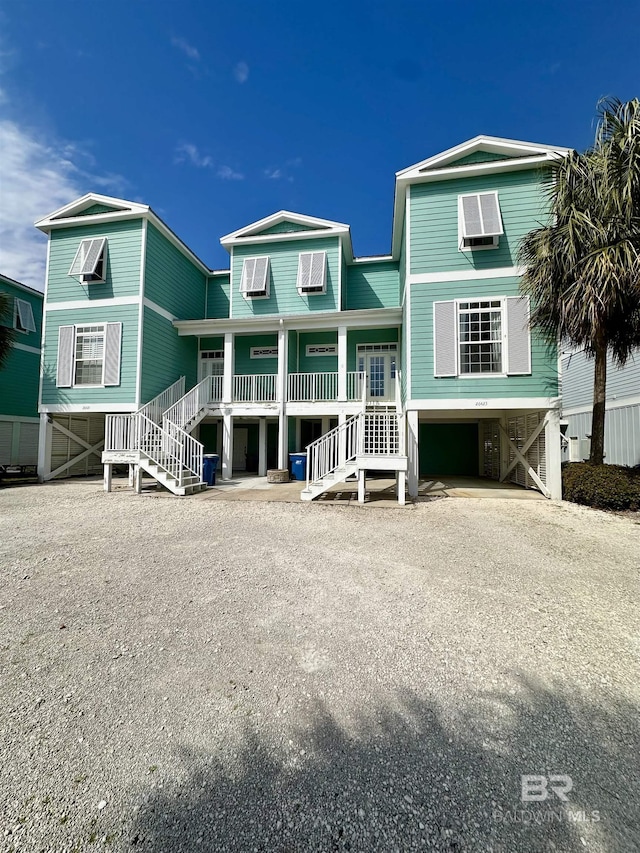 view of front of house with driveway, stairway, a wall mounted air conditioner, a porch, and a carport