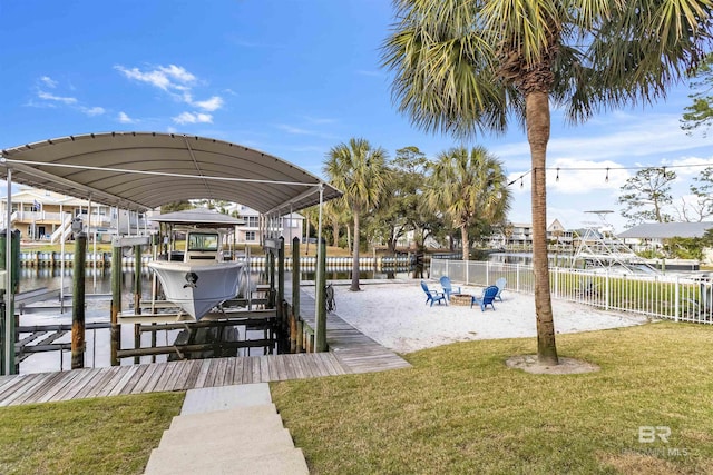 dock area featuring a lawn, boat lift, and fence