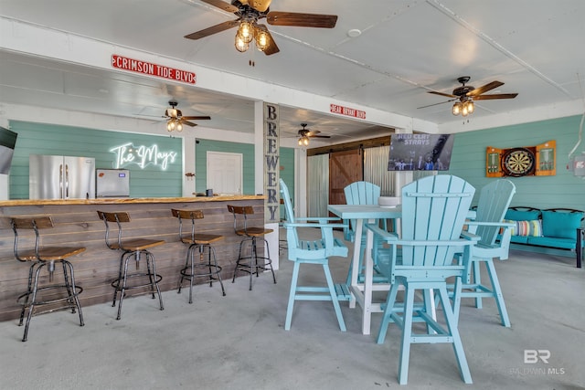 dining space featuring concrete flooring, a bar, and wooden walls