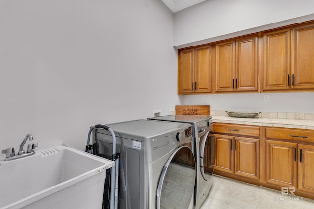 clothes washing area featuring cabinet space, a sink, and washer and clothes dryer